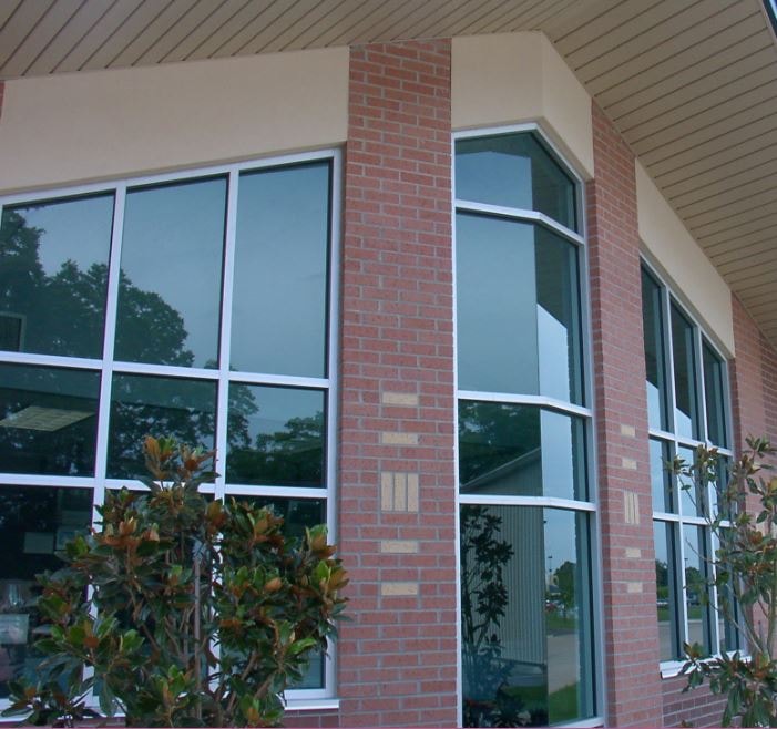 Brick building exterior with large curtain wall windows and landscaping