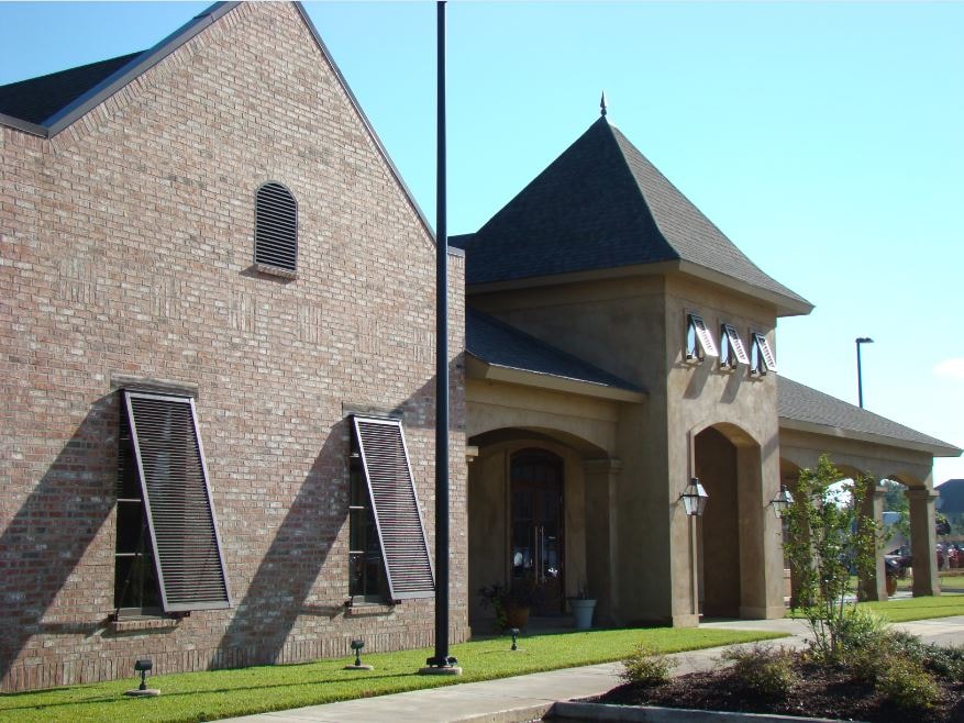 Brick and stucco building exterior with arched entry tower and shutters
