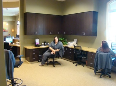 Dental office administrative area with dark cabinetry and staff at desks