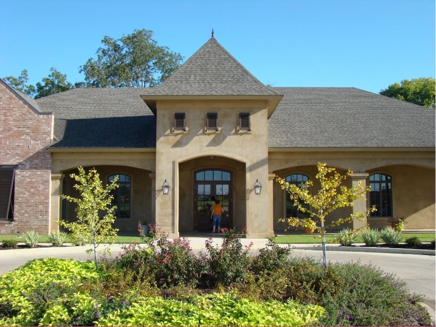 French stucco home front facade with arched windows and landscaping