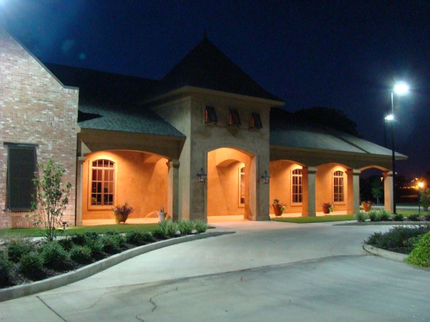 Stucco and brick building exterior at night with illuminated arched porticos