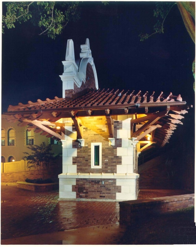 Illuminated historic plaza pavilion with red tile roof and brick masonry at night