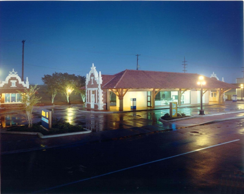 Historic transit plaza wide view at night with illuminated buildings and wet pavement