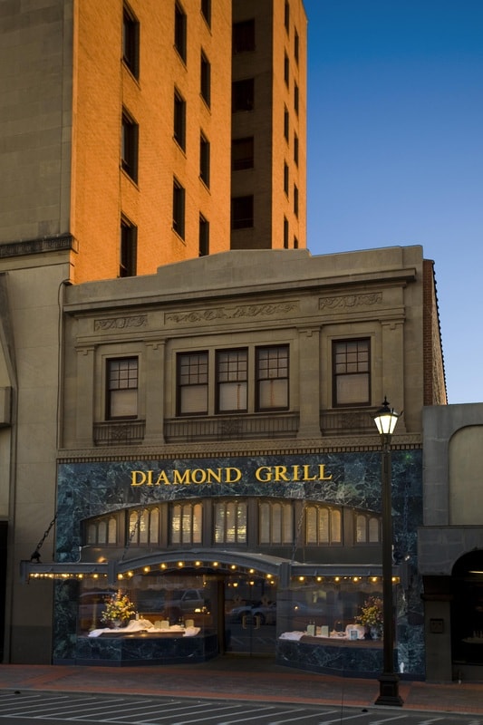 Multi-story commercial building facade with dark steel curtain wall and stone cladding